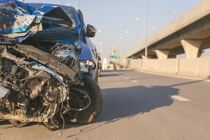 blue vehicle on highway with severe front damage