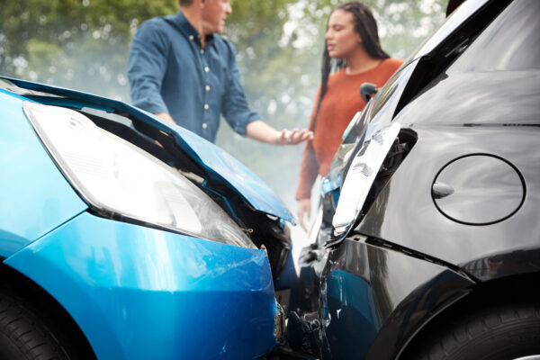 An uninsured driver stressed, speaking with another driver after a car accident.