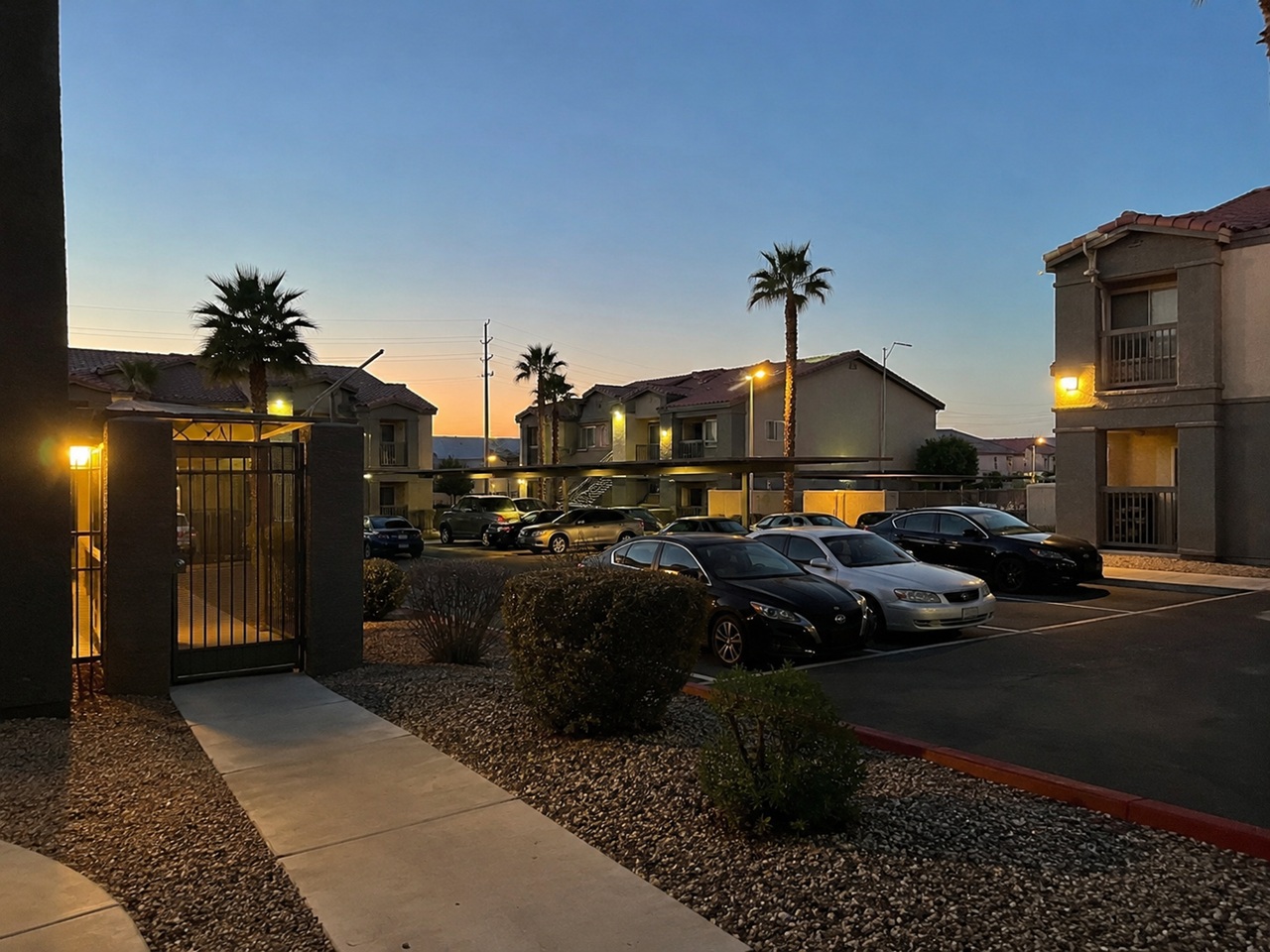A dimly lit Las Vegas apartment complex parking lot and gated walkway at dusk, illustrating the poor lighting and security conditions relevant to negligent security claims.